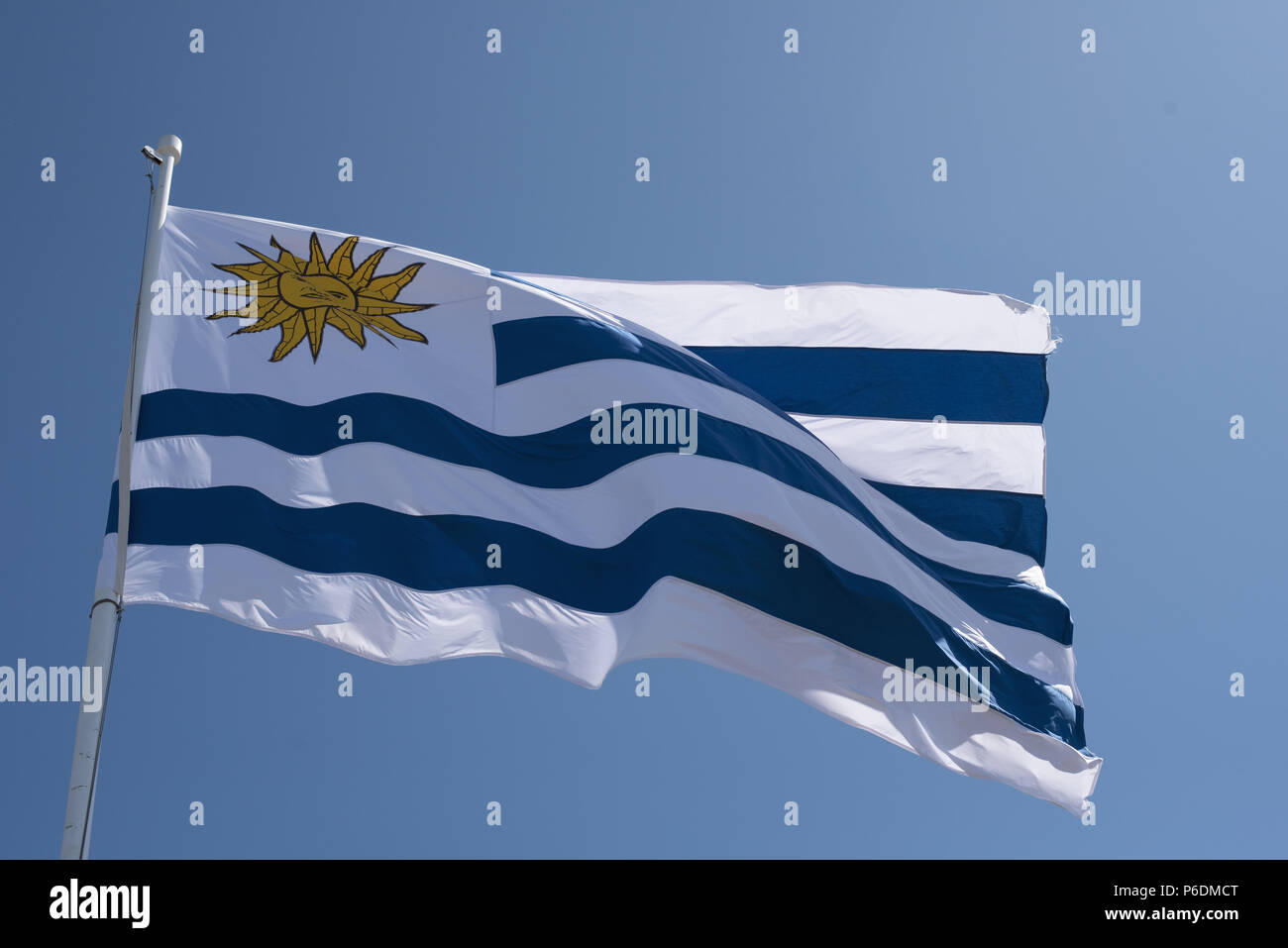 Uruguayische Fahne im Wind auf und blauer Himmel. Uruguay land Fahnenmast mit nationalen Emblem. Stockfoto