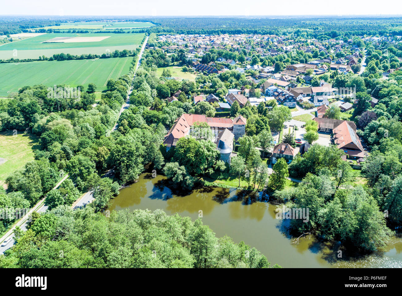 Luftaufnahme von einem deutschen Dorf mit einem kleinen Wald, ein Teich und ein Wasserschloss im Vordergrund, in der Nähe von Wolfsburg. Stockfoto