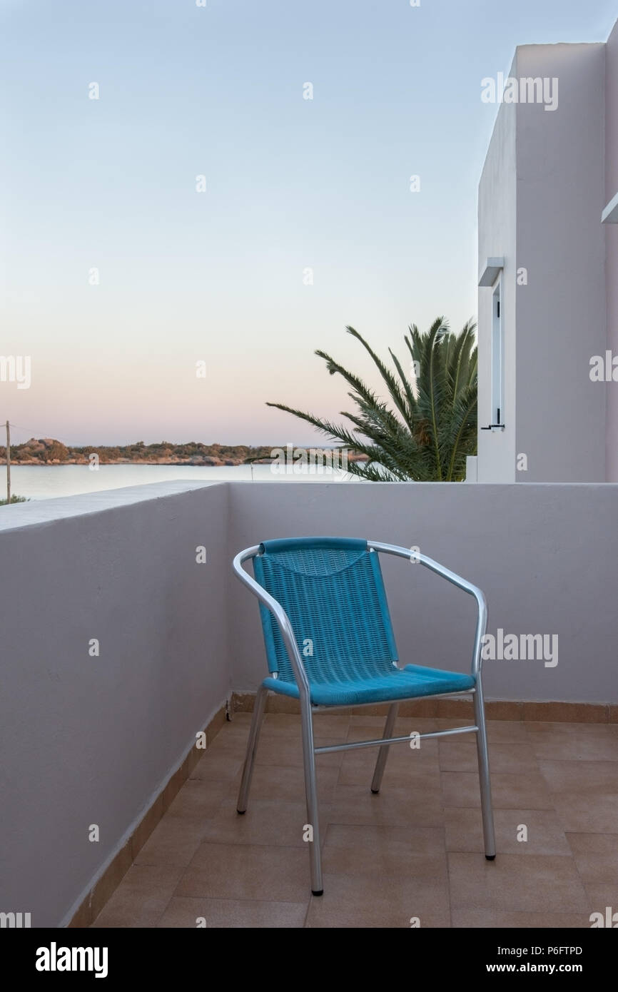 Blaue Stuhl auf der Terrasse mit Blick auf das Meer im Sonnenuntergang Stockfoto