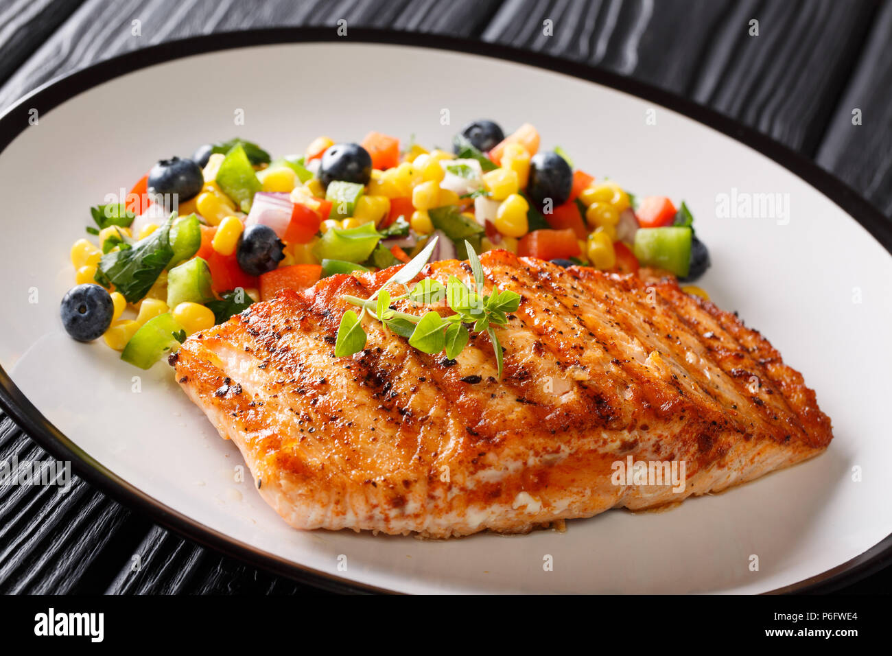 Gegrilltes Steak Lachs mit Paprika, Mais, Blaubeere und Zwiebel Salat closeup auf dem Teller auf dem Tisch. Horizontale Stockfoto