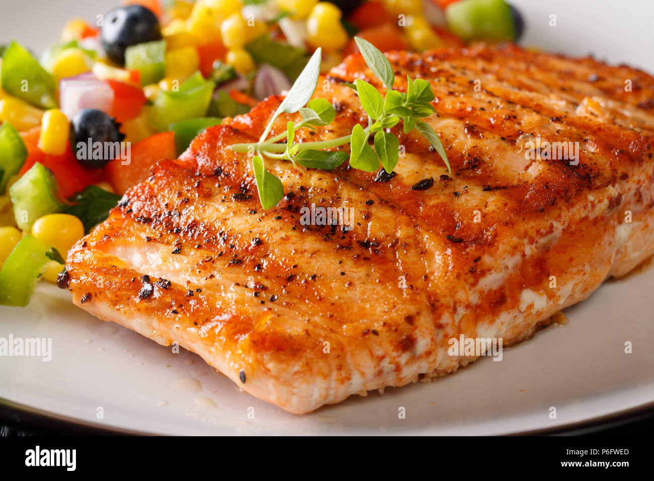 Gegrilltes Lachsfilet mit Salsa von Mais, Blaubeeren und Pfeffer Makro auf einem Teller. Horizontale Stockfoto