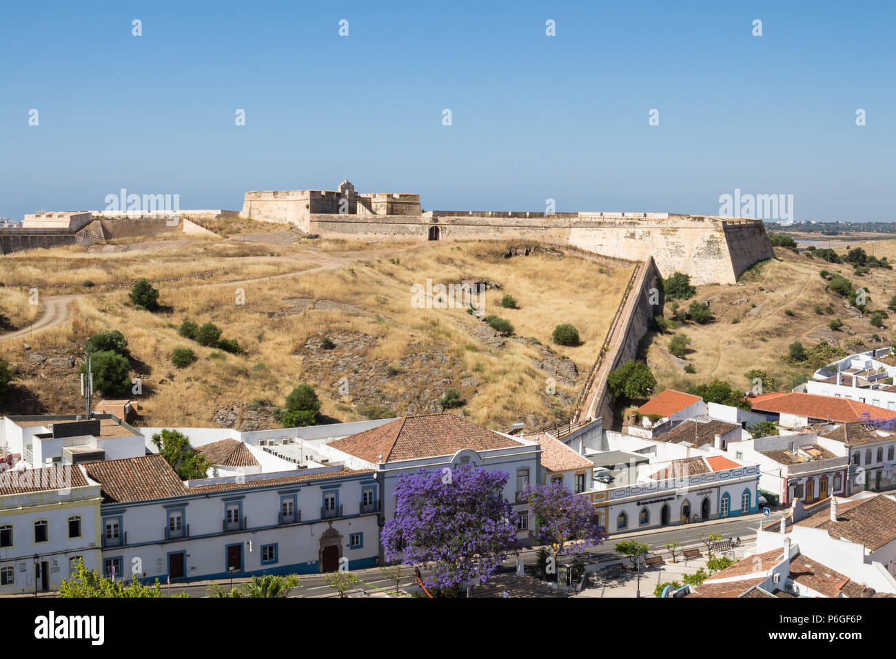 Häuser von Castro Marim und einem Ausblick auf die mittelalterliche Festung auf dem Hügel mit dem gleichen Namen, durch die Schutzmauer umgeben. Strahlend blauen Himmel. Castro Mar Stockfoto