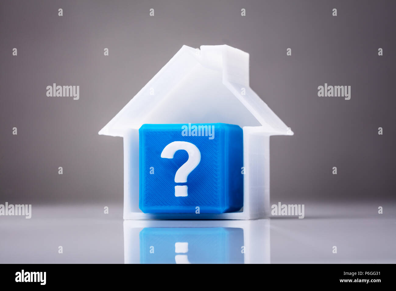Blue Cube mit Fragezeichen Zeichen im Haus Modell auf reflektierenden Hintergrund Stockfoto