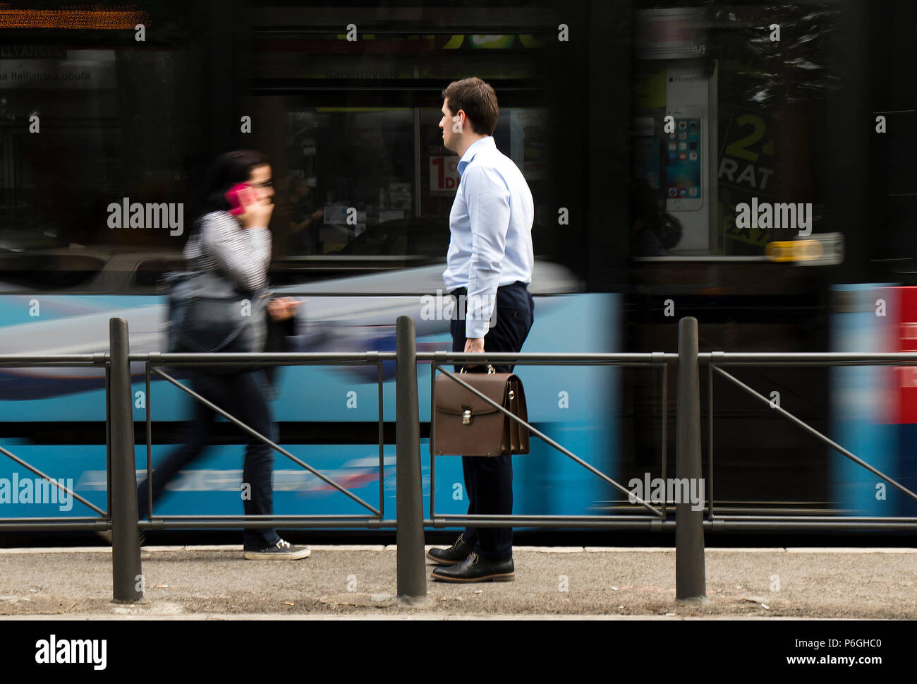 Belgrad, Serbien - April 24, 2018: Ein white-collar Mann mit Aktentasche steht an einer Bushaltestelle und Warten auf öffentliche Verkehrsmittel mit verschwommenen motio Stockfoto