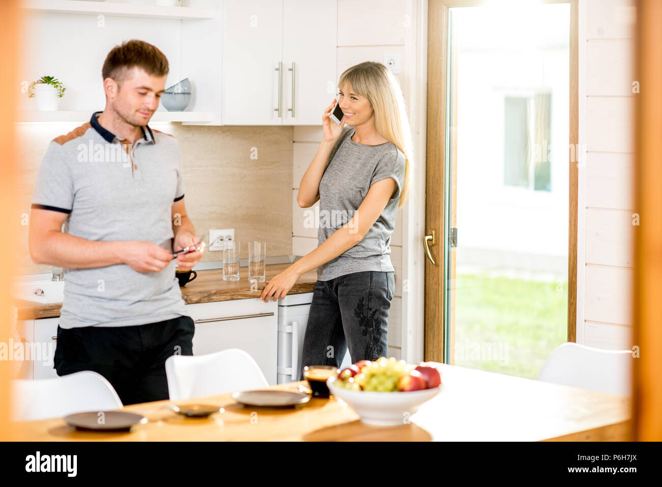Junges Paar Gerichte und sprechen Telefon Vorbereitung für das Abendessen in der Küche des modernen Country House Stockfoto