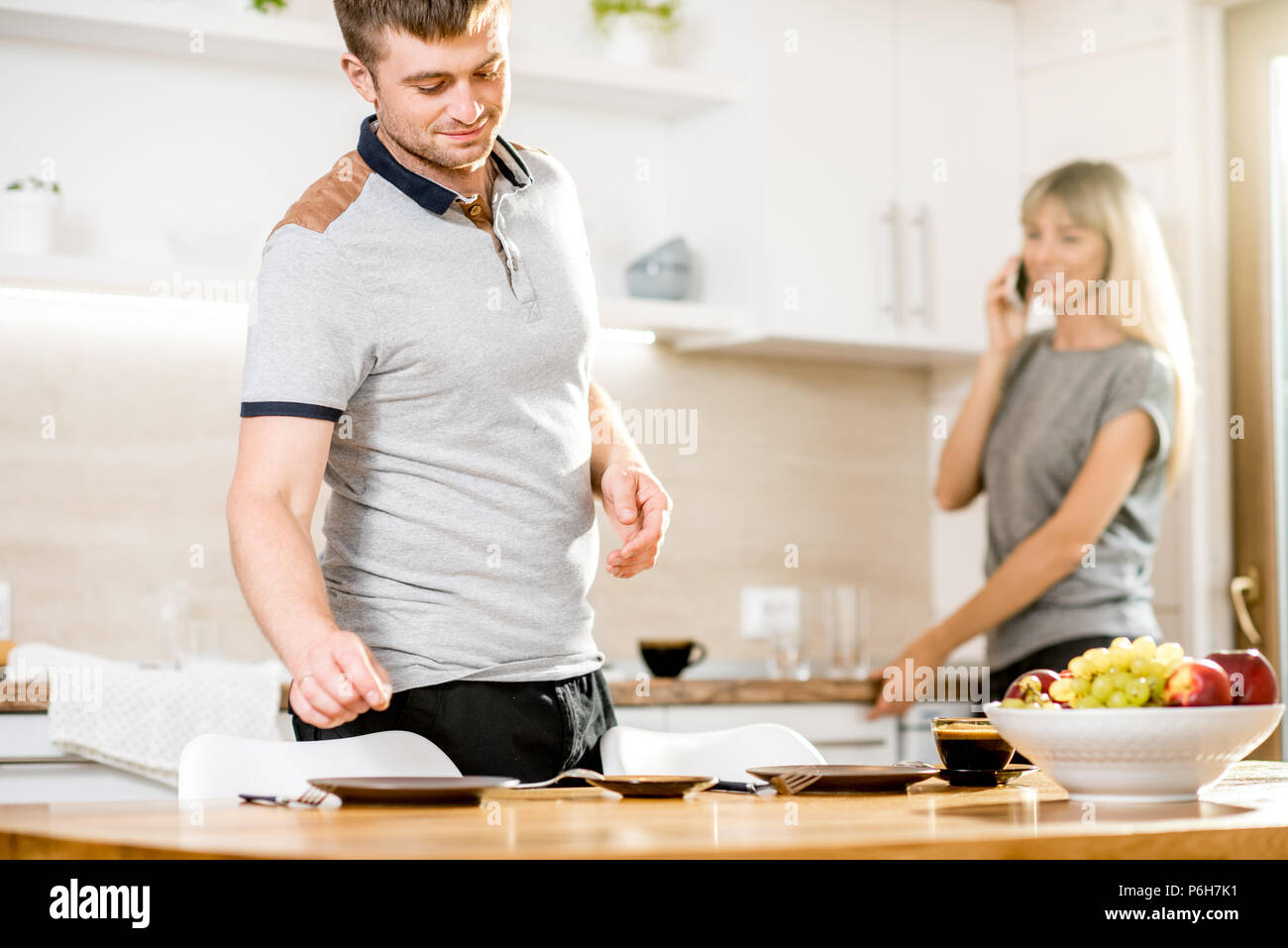 Junges Paar Gerichte und sprechen Telefon Vorbereitung für das Abendessen in der Küche des modernen Country House Stockfoto