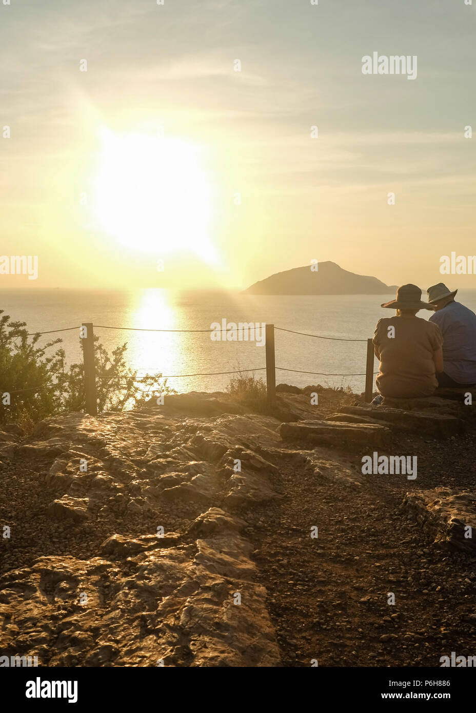 Hatted Paar genießt die Aussicht auf den Ozean von Kap Sounion (Tempel des Poseidon) Wie die Sonne beginnt zu setzen. Ost Attika, Griechenland. Stockfoto