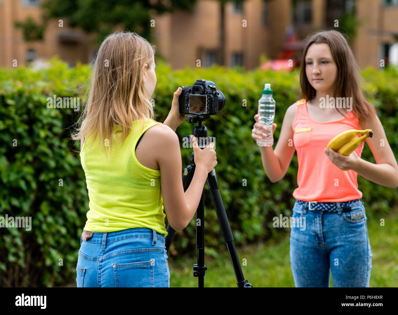 Sommer in der Natur zum Girl Schoolgirl. Schreibt das Video auf der Kamera. In ihren Händen hält eine Flasche Wasser und Bananen. Das Konzept der gesunden Ernährung. Stockfoto