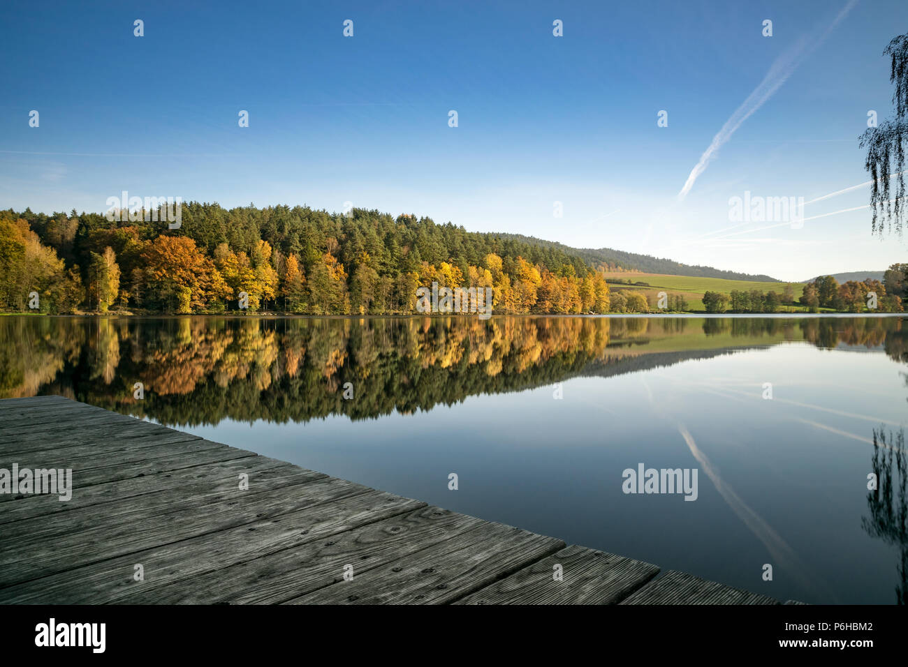 Steg am See im Herbst mit orange und gelb Bäume und Reflexion von den Wald auf dem Wasser im Bayerischen Wald Stockfoto