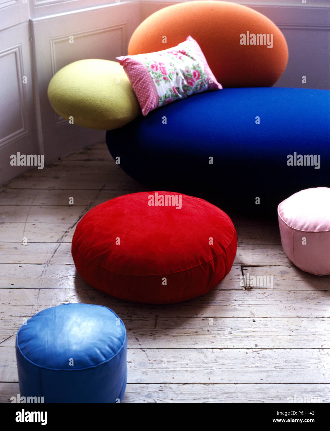 Bunte runde Samt und Leder, Kissen auf Holzboden neben einem Blau und Orange retro Samtsofa Stockfoto