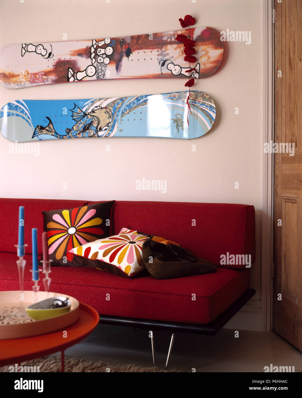 Gemusterte skateboards an der Wand über dem roten Sofa mit hellen Kissen in modernen Wohnzimmer Stockfoto