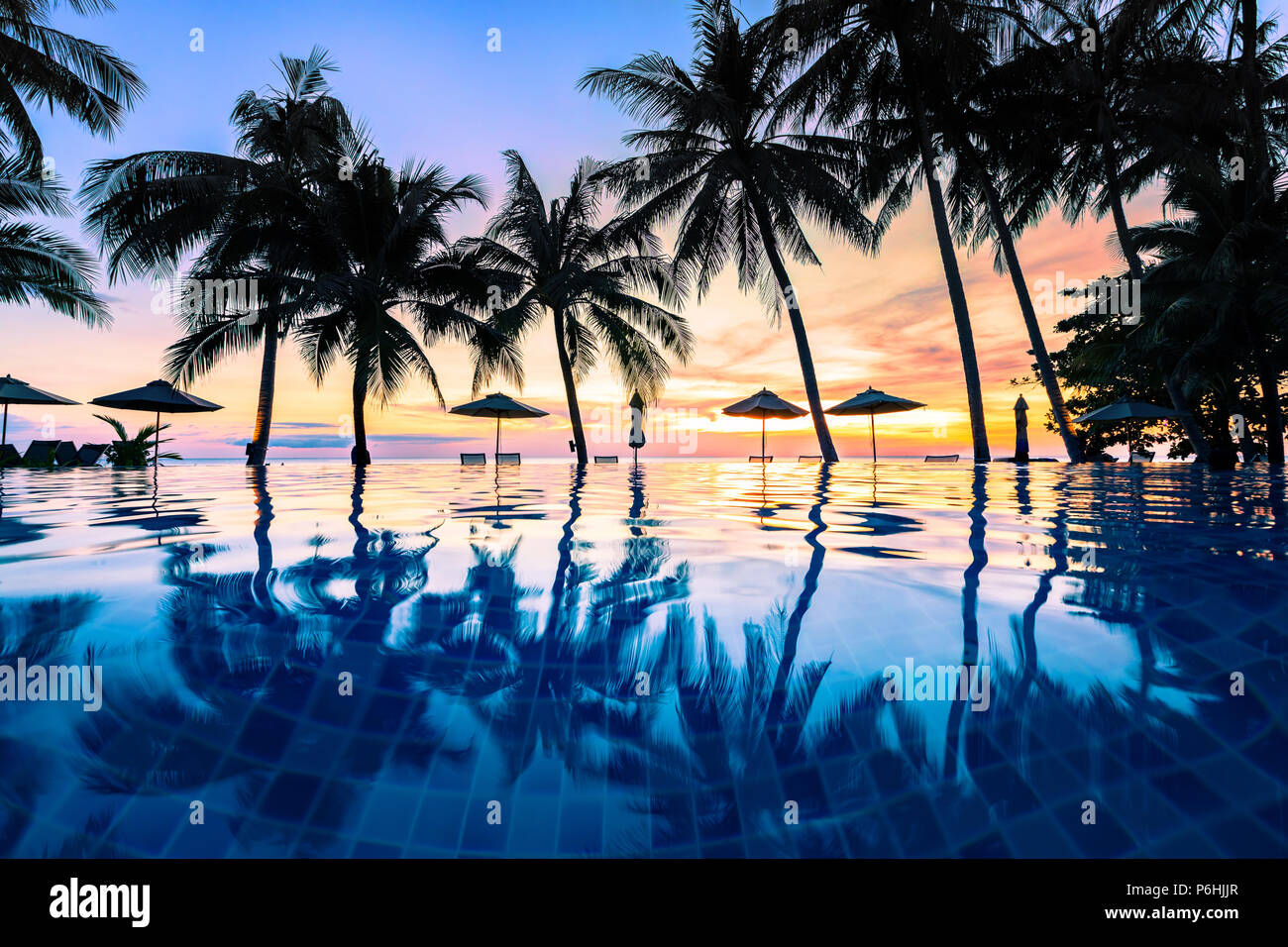 Sommer Strand Urlaub Urlaubsziel, luxuriöse Resort am Strand Schwimmbad mit tropischer Landschaft, Ruhige warme Sonnenuntergang, Silhouette und Reflexionseigenschaften Stockfoto