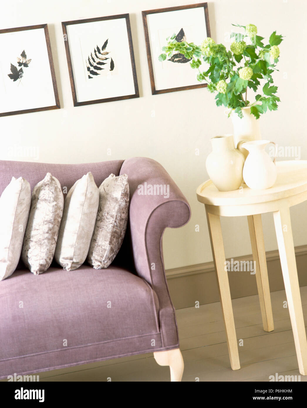 Drei gedrückt - Leaf Bilder an der Wand oben mauve Sofa im Wohnzimmer mit einer Gruppe von Cream jugs auf kleinen creme Tabelle Stockfoto