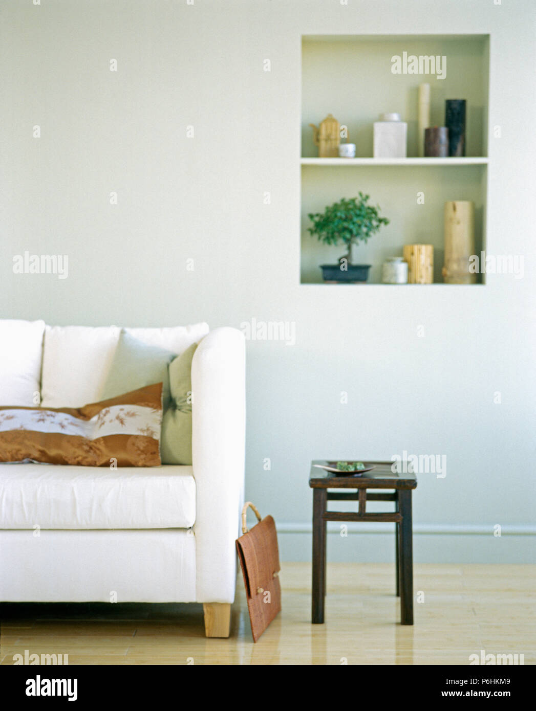 Weiß Sofa und kleine schwarze Hocker in modernes Wohnzimmer mit Bonsai und Sammlung von Vasen auf Alkoven Regale Stockfoto