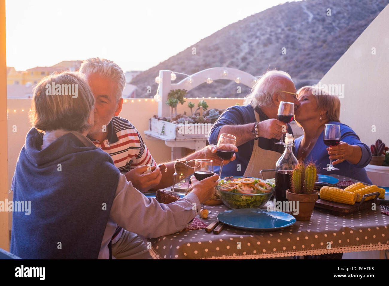 Nette Gruppe der kaukasischen erwachsener Menschen in Glück bleiben zusammen für Abendessen im Freien auf der Terrasse. liebe und freundschaft Konzept mit herrlichen Ausblick. v Stockfoto