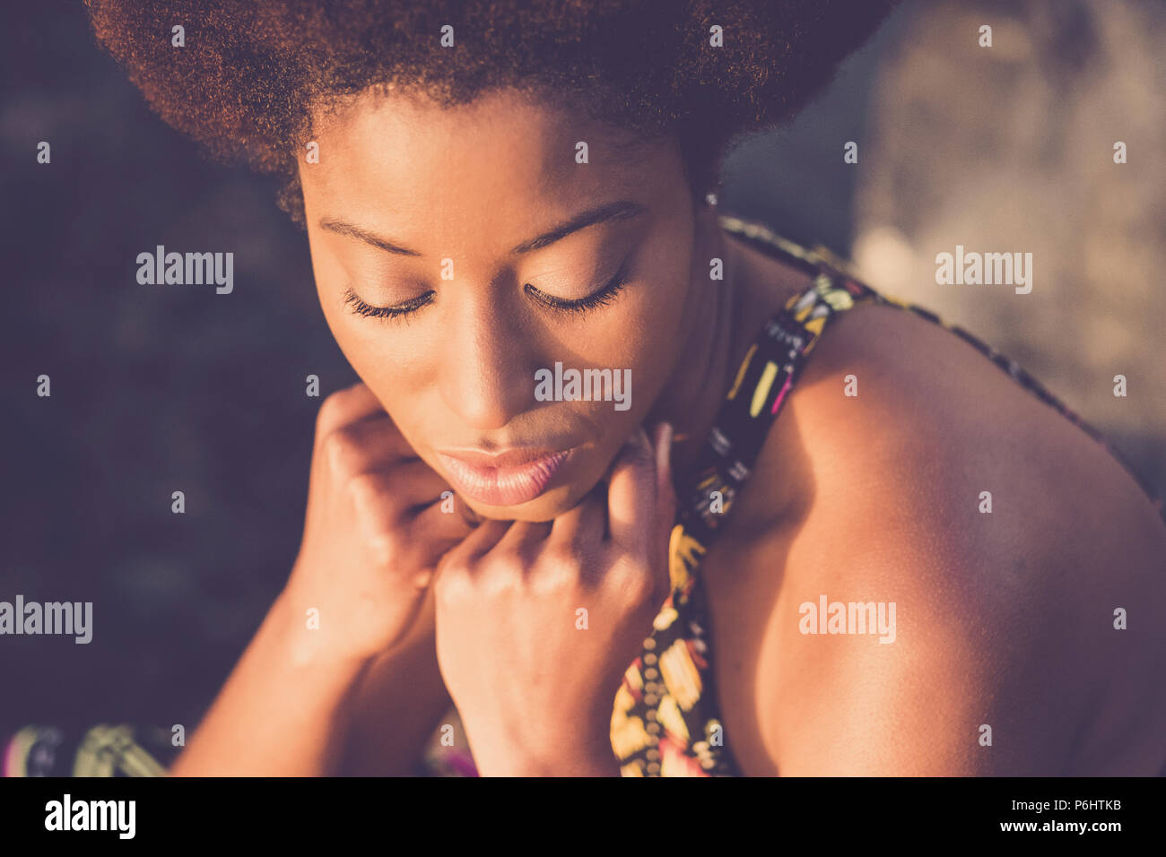 Schönen schwarzen Rasse afrikanische afro Haar Modell mit geschlossenen Augen und mit der Hand auf dem Gesicht Pose unter dem Sonnenlicht. Schönheit Konzept für schwarze Haut und an Stockfoto