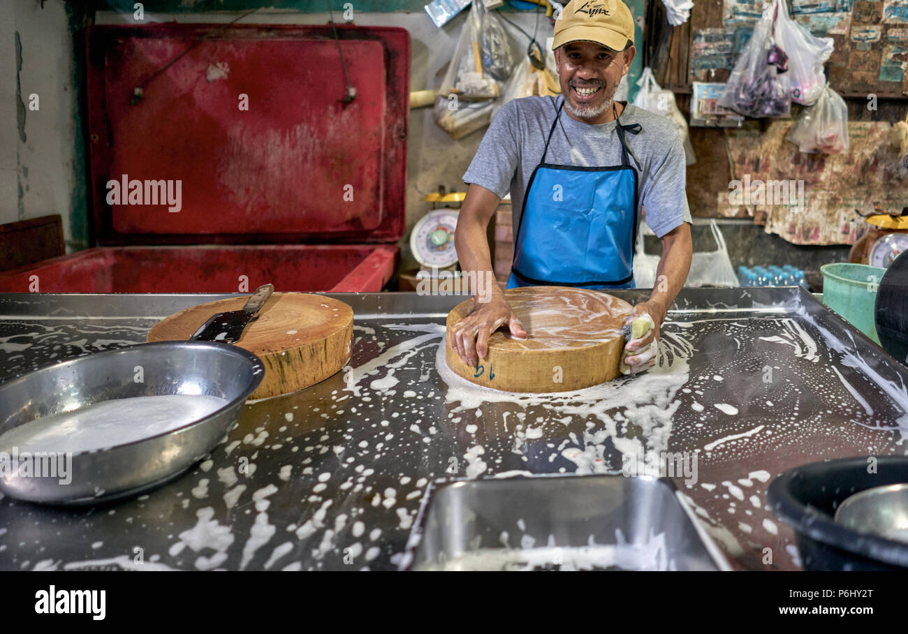 Mann, der Aufgaben erledigt. Thailand Marktanbieter. Mann putzt und schrubbt Geschirr Stockfoto