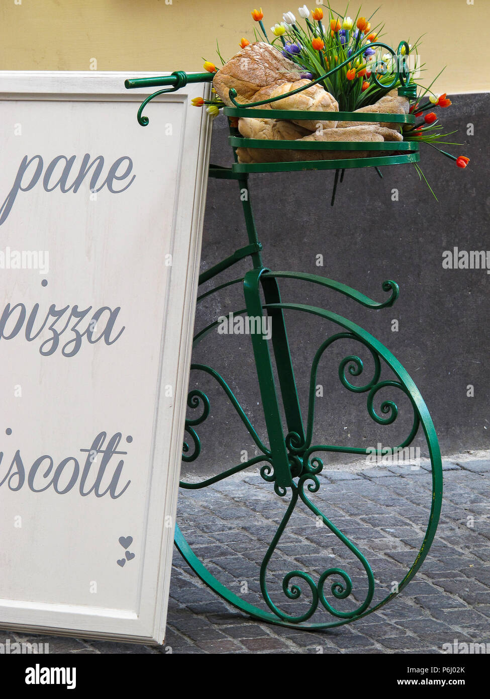 Grüne Fahrrad- und weisses Schild, mit der Aufschrift "Brot, Plätzchen und Pizza", auf einer Straße in Viterbo (Italien) Stockfoto