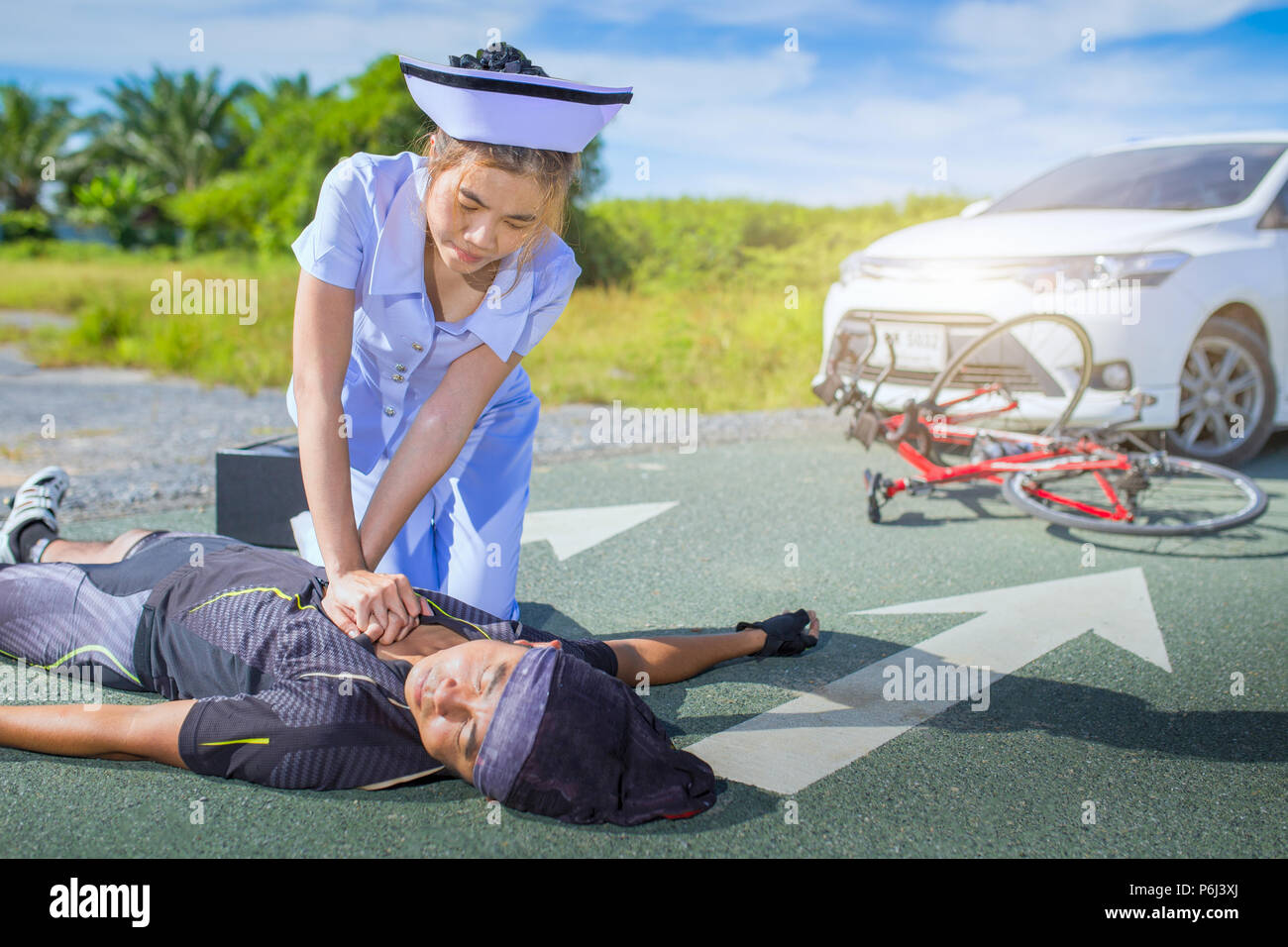 Weibliche Krankenschwester helfen, Not-HLW-Radfahrer verletzt auf der Straße Fahrrad nach Asien nach Zusammenstoß Unfall Auto und Motorrad Stockfoto