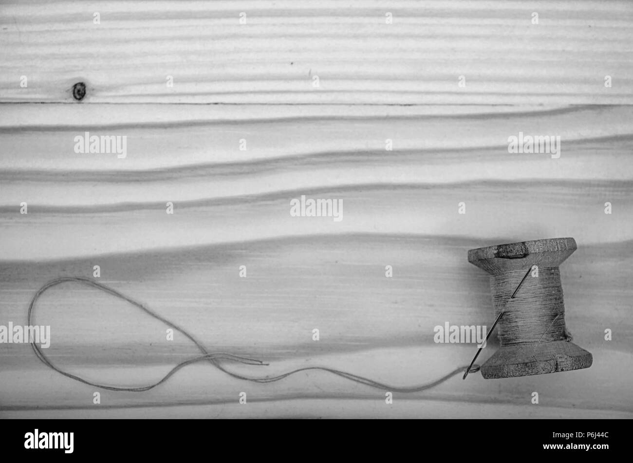 Die alte Haspel der Gewinde- und eine Nadel auf einen hölzernen Tisch in Schwarz und Weiß. Stockfoto