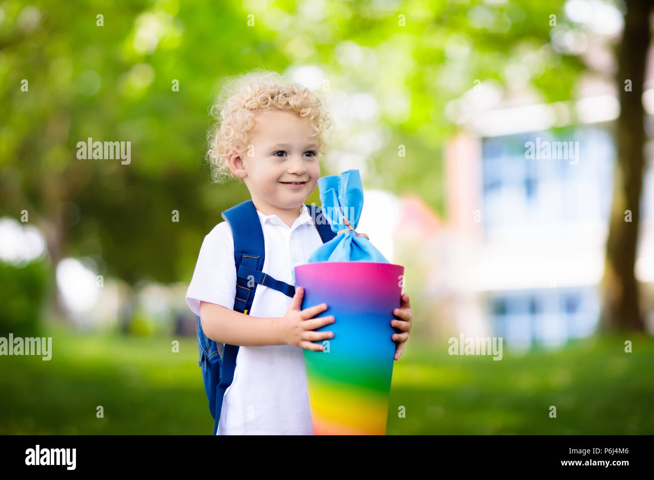 Glückliches Kind Holding traditionelle deutsche candy Kegel auf der erste Schultag. Wenig Kursteilnehmer mit Rucksack und Bücher aufgeregt zurück zu Schule zu werden. Anfang Stockfoto
