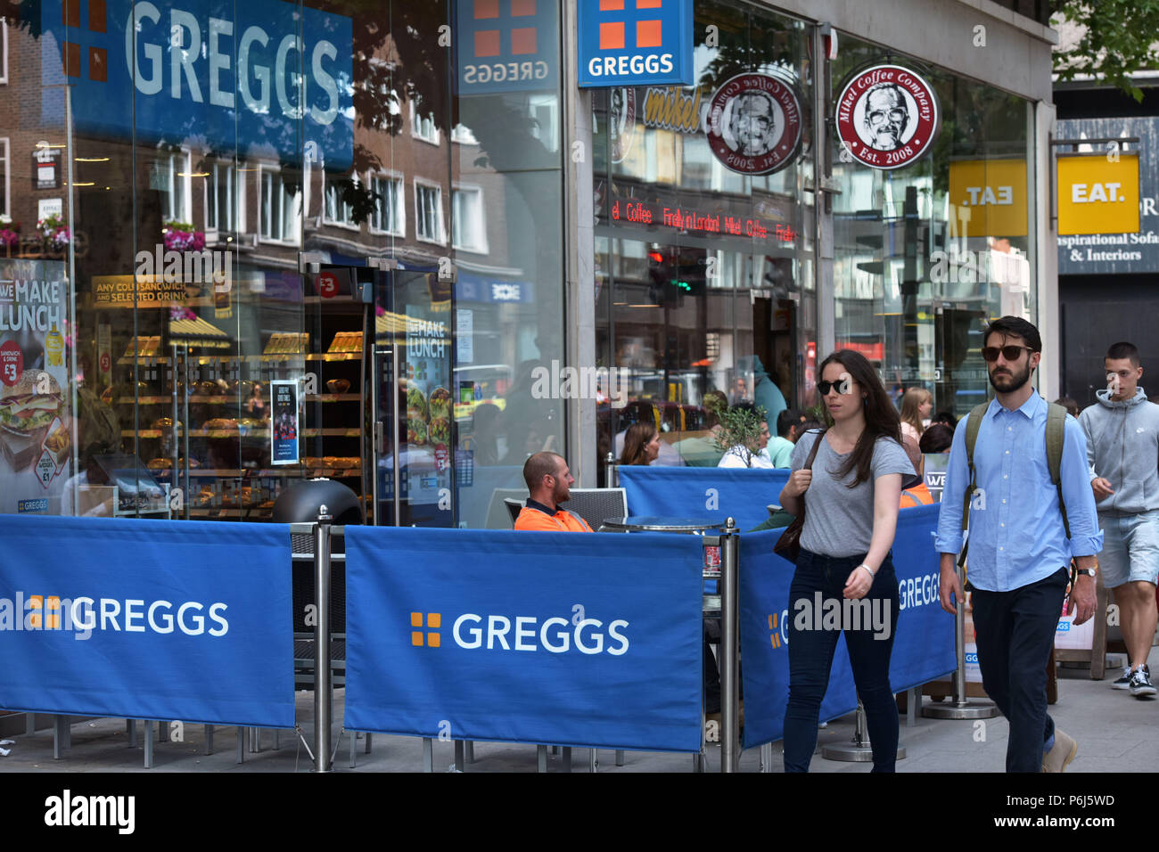 Menschen gehen vorbei an einer Reihe von Cafés und Take-away Läden einschließlich sandwichmaker und Bäckerei Greggs, Mikel Kaffee und Essen. der Tottenham Court Road in Stockfoto