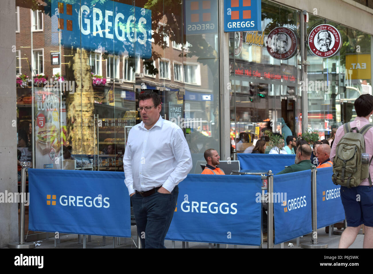 Menschen gehen vorbei an einer Reihe von Cafés und Take-away Läden einschließlich sandwichmaker und Bäckerei Greggs, und Mikel Coffee Company auf Tottenham Court Road. Stockfoto