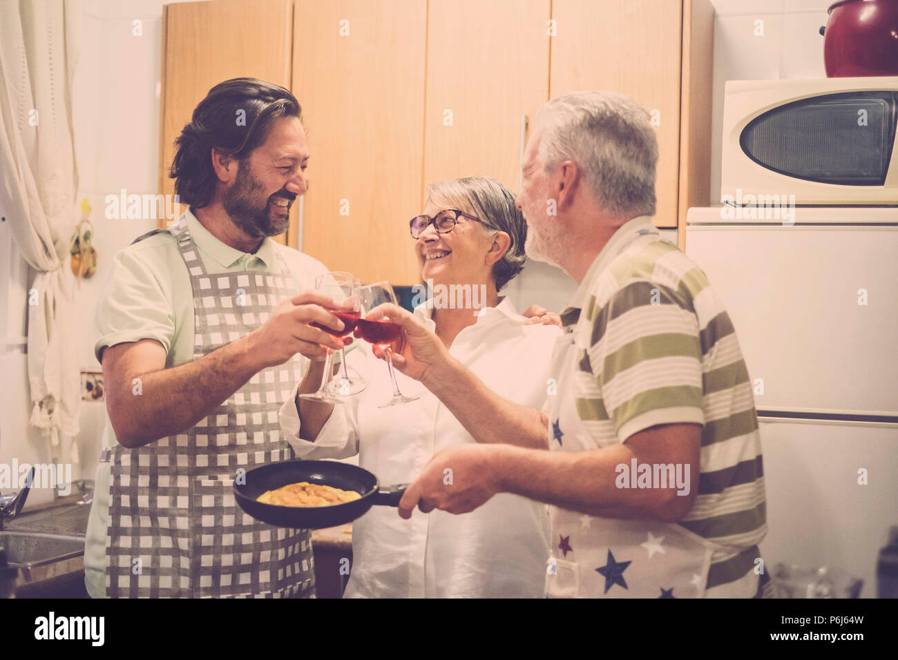 Vater und Sohn nach Essen und Kuchen in der Küche für eine Familie Szene Konzept vorbereiten. Das tägliche Leben zu Hause mit zwei Mann und eine Frau. Zwei Senioren- und eine m Stockfoto