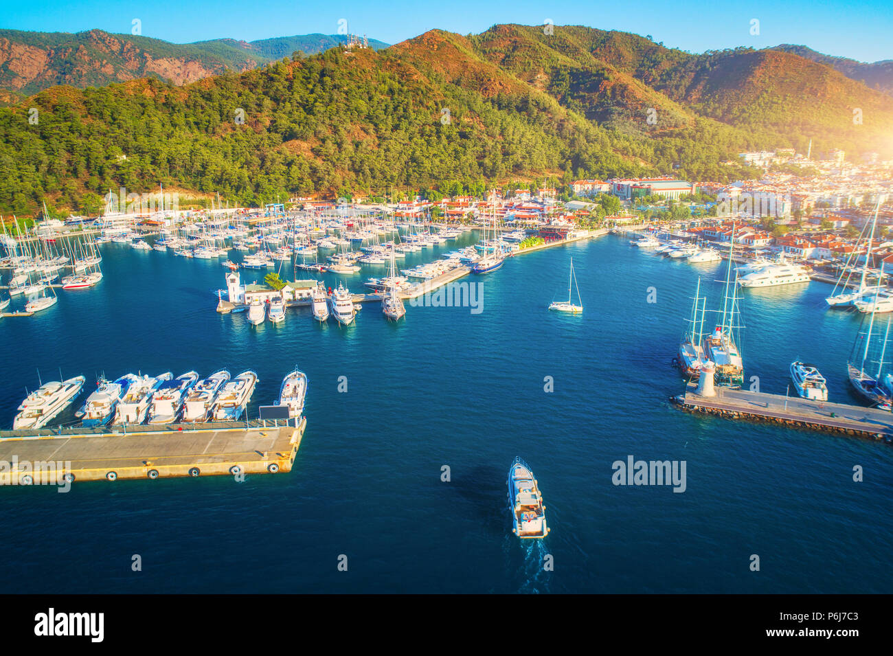 Luftaufnahme von Booten und Yachten bei Sonnenuntergang in der Türkei. Bunte Landschaft mit Marina Bay, blaues Meer, Berge, Wald, blauer Himmel. Ansicht von oben von drohne von Stockfoto