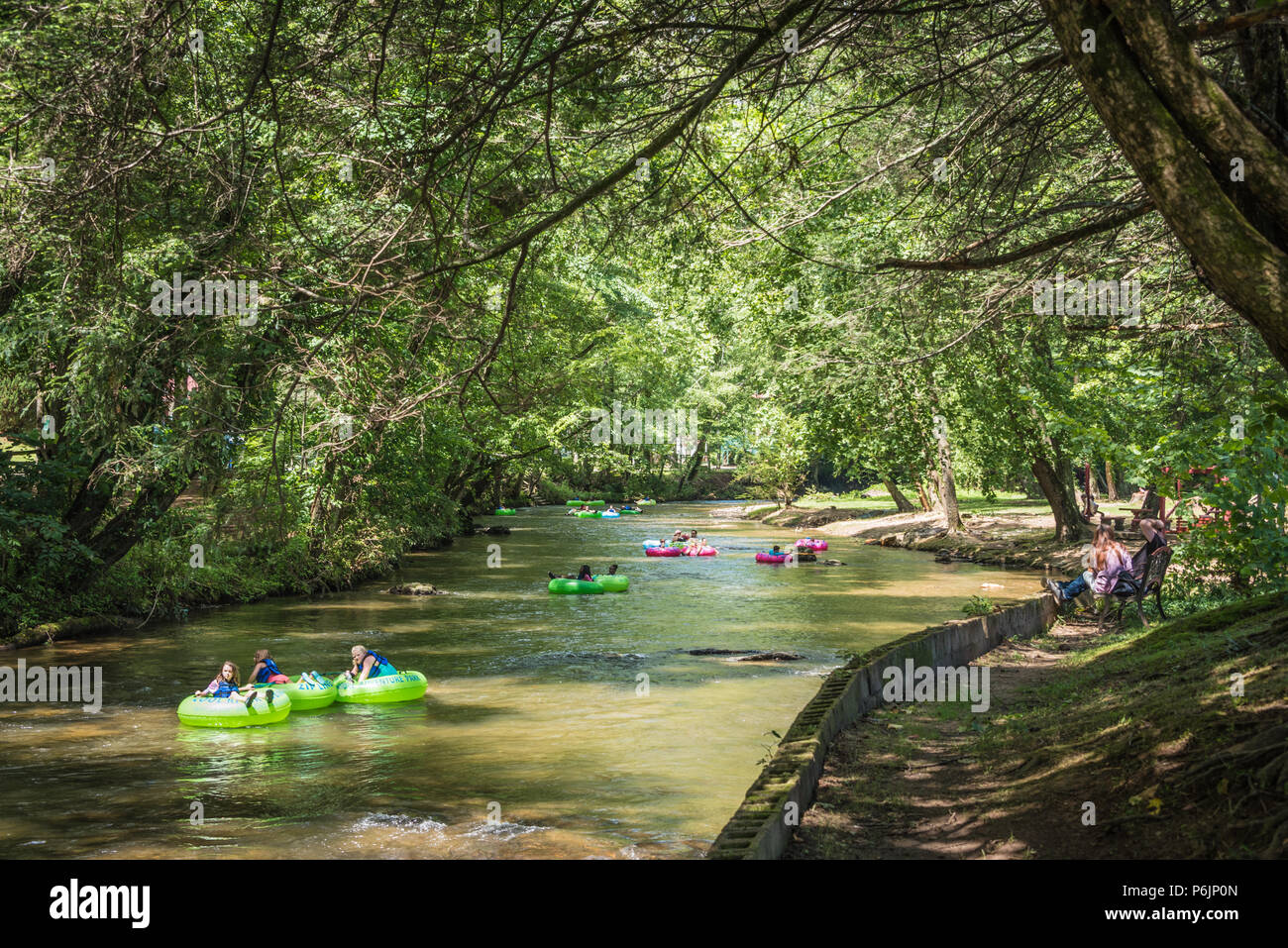 Die Menschen genießen einen entspannenden Sommertag unter einer überdachung der Bäume am Chattahoochee River in Helen, Georgia. (USA) Stockfoto