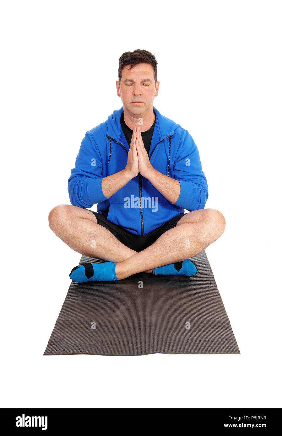 Eine meditierende Mann in einer blauen Jacke auf dem Boden sitzend in einer Yoga pose mit geschlossenen Augen und Hand gefaltet, auf weißem Hintergrund Stockfoto
