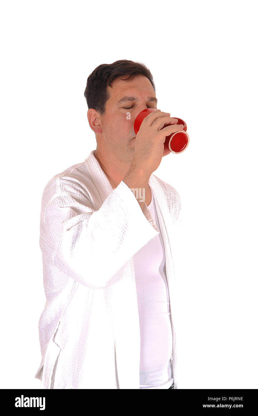 Ein schöner großer Mann in einem weißen Bademantel und das Trinken aus einer roten Kaffeetasse, auf weißem Hintergrund Stockfoto
