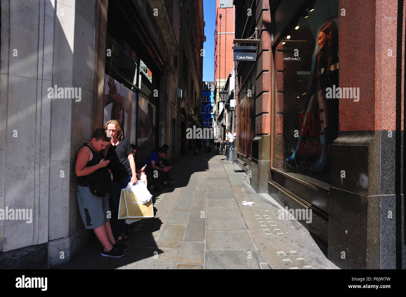 Mutter und Kind Schutz vor der Sonne in der Gasse zwischen Regent Street und Canarby Street, London, England, Großbritannien Stockfoto