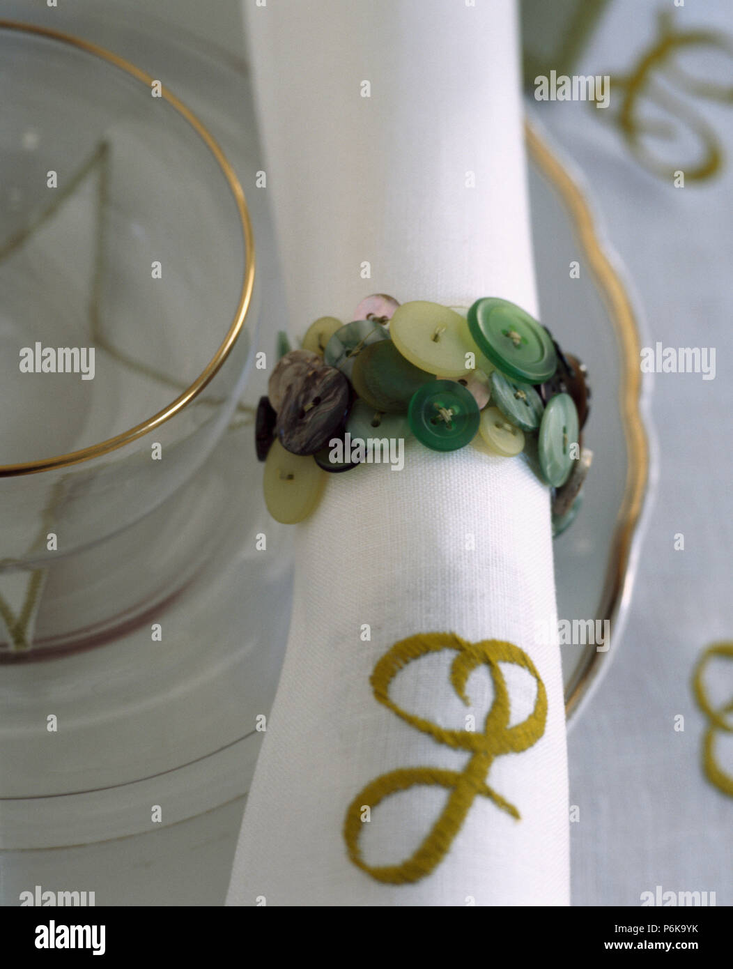Close-up monogrammed weiße Bettwäsche tisch Serviette mit der grünen Taste Serviettenring Stockfoto