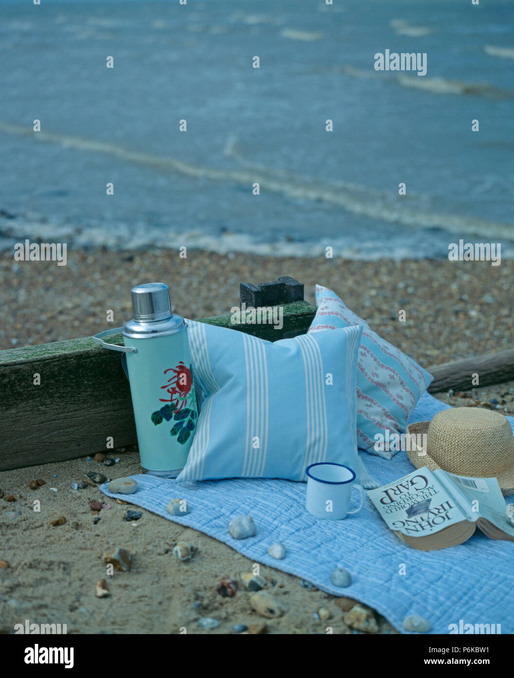 Nahaufnahme von blassen blauen Kissen und Chinesisch-gemusterten Thermoskanne auf Baumwolle Teppich am Strand Stockfoto