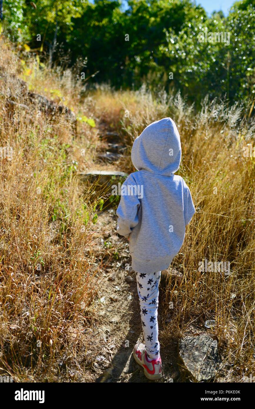 Kleines Kind zu Fuß durch langes Gras mit Grauer Hoodie, von hinten, viele Gipfel wanderung Berg Marlow, Townsville Stadt gemeinsame Queensland, 4810, Australien Stockfoto