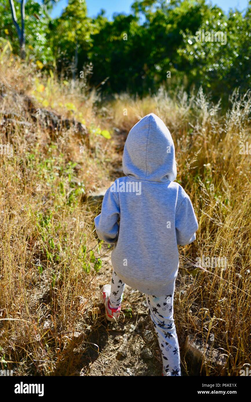 Kleines Kind zu Fuß durch langes Gras mit Grauer Hoodie, von hinten, viele Gipfel wanderung Berg Marlow, Townsville Stadt gemeinsame Queensland, 4810, Australien Stockfoto