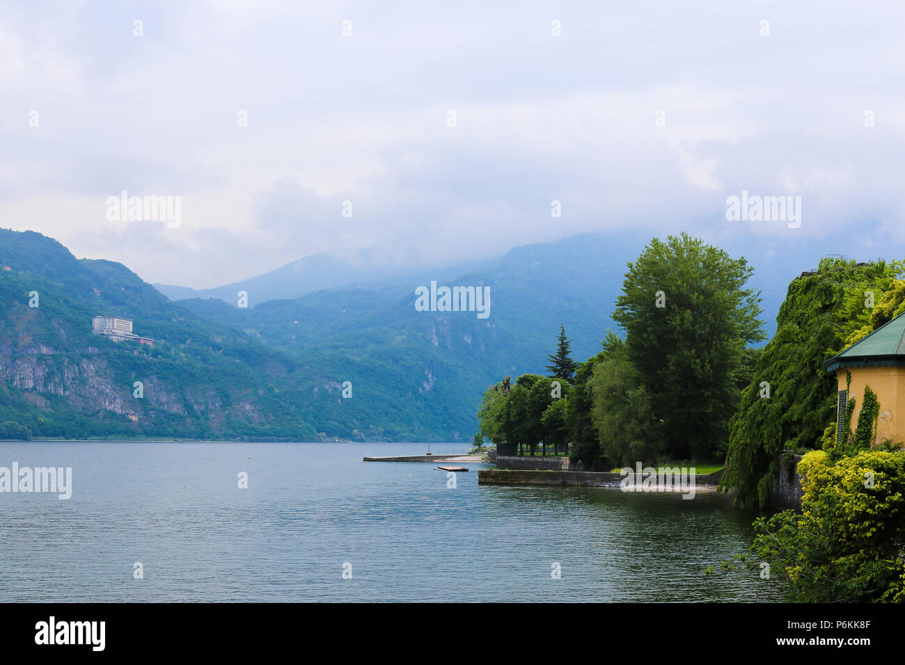 Zaun mit Efeu und kleine Gebäude in der Nähe des Meer, mouintain ich Hintergrund. Stockfoto