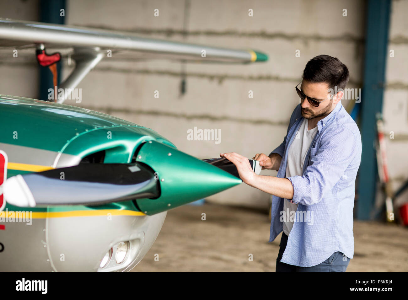 Hübscher junger Pilot Kontrolle Flugzeug im Hangar Stockfoto