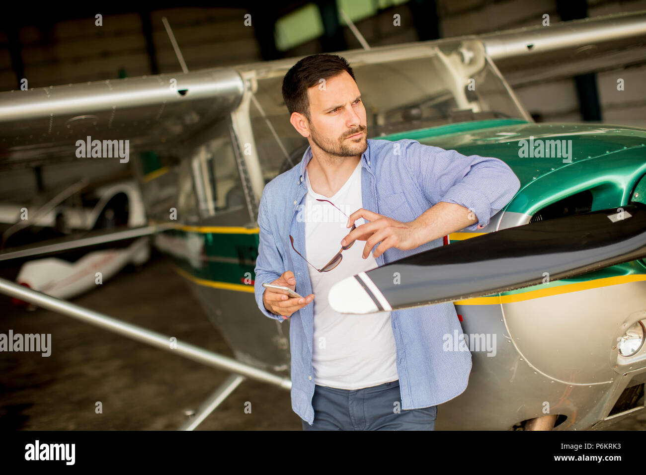 Hübscher junger Pilot Kontrolle Flugzeug im Hangar Stockfoto