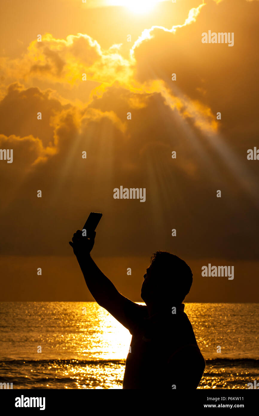 Silhouette der junge Mann ein selfie gegen Meer bei Sonnenaufgang Stockfoto