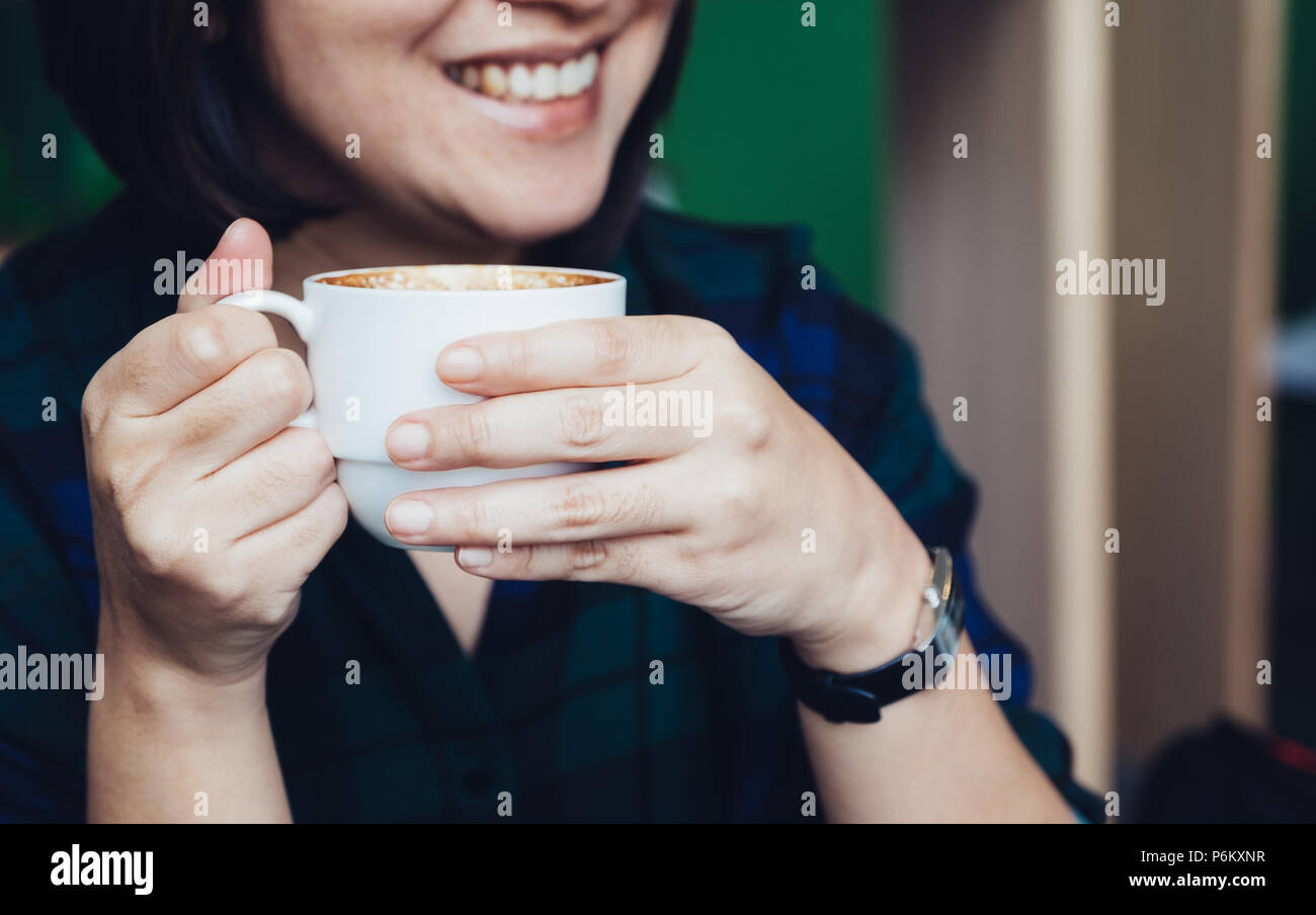 Nahaufnahme, Frau, Hand, die heißen Cappuccino Tasse mit lächelnden Gesicht im Cafe Shop, Freizeit Aktivität Stockfoto