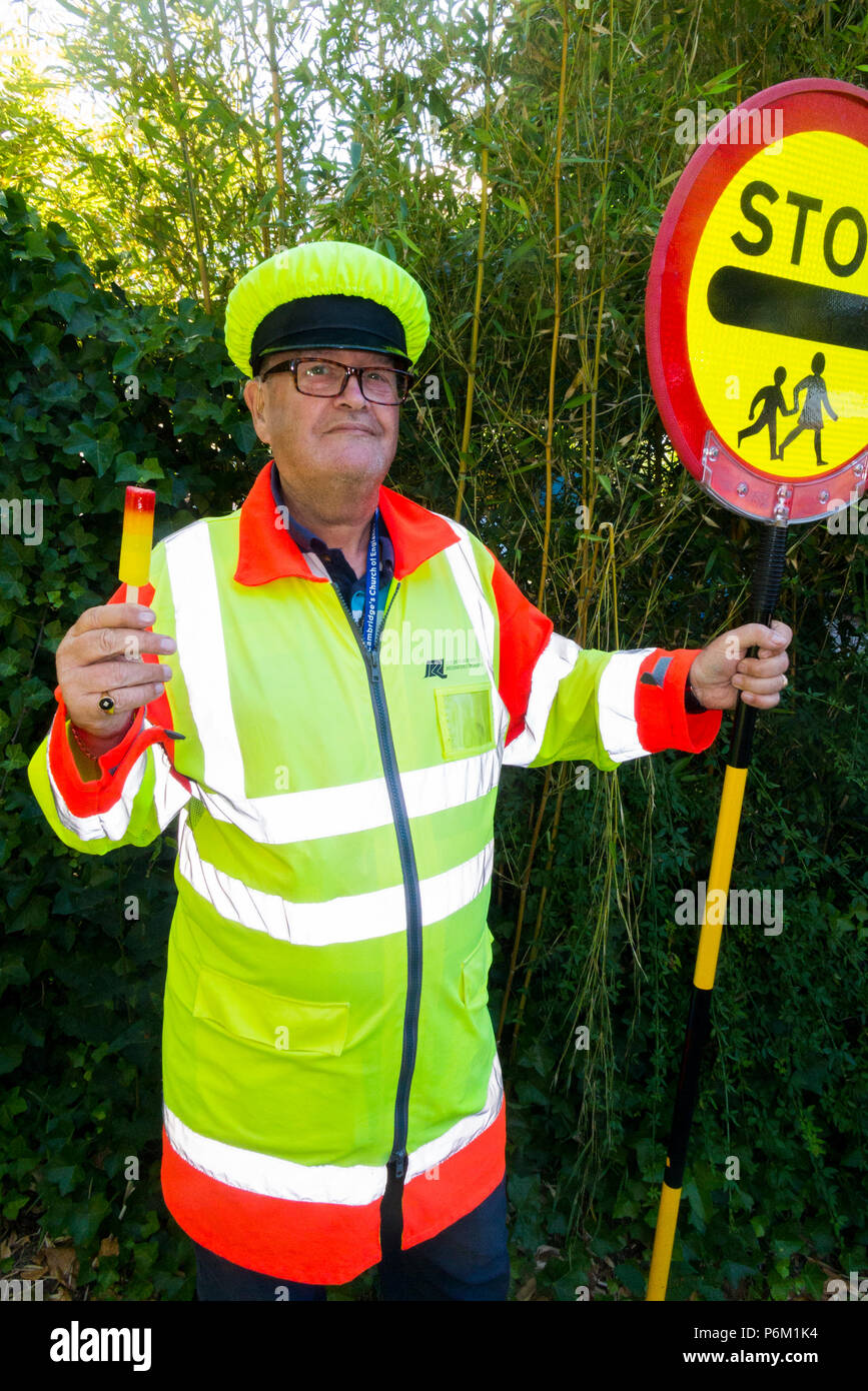 Iollipop Mann, der gerade seine Schicht an der Schule überqueren Zebrastreifen abgeschlossen hat. Er ist Abkühlung mit einem Lutscher das in derselben Farbe wie sein Outfit. England, Großbritannien Stockfoto