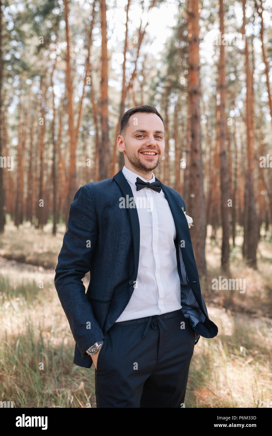 Jungen netten Mann in einem weißen Hemd Business Anzug mit Fliege steht an der Natur im Park und lächelt glücklich erfolgreiches Leben Konzept. Stockfoto