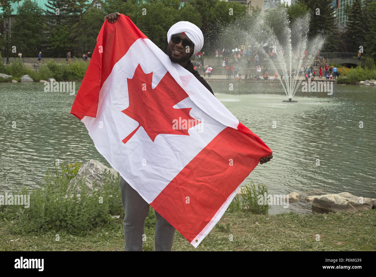 Kanada-Tag. Der Mann hält die kanadische Flagge, nachdem er Turban, eh?, eine Veranstaltung der World Sikh Organization im Prince's Island Park in Calgary am Canada Day, festgebunden hat. Die Menschen wurden eingeladen, einen roten oder weißen Turban um ihren Kopf wickeln zu lassen und mehr über die Sikh-Kultur zu erfahren. Rosanne Tackaberry/Alamy Live News Stockfoto