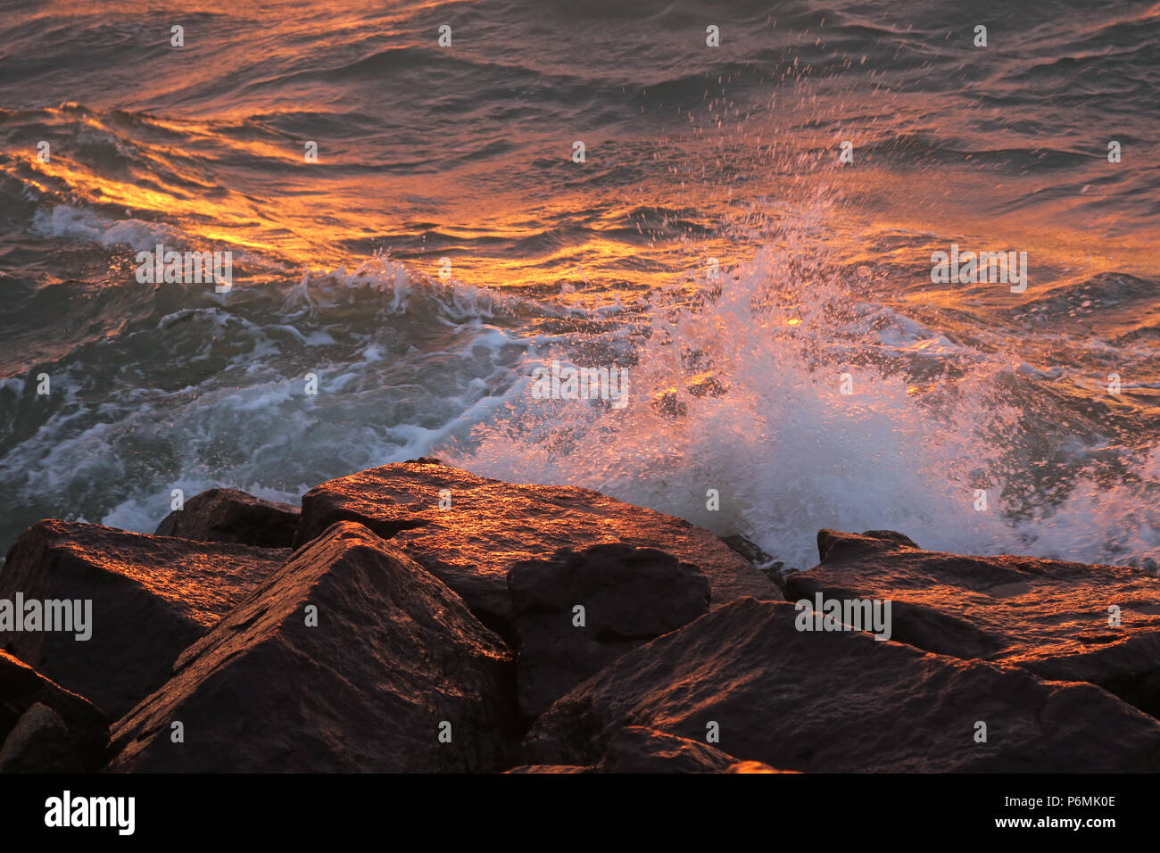 Warnemünde, Wellen im Abendlicht auf Felsen brechen Stockfoto