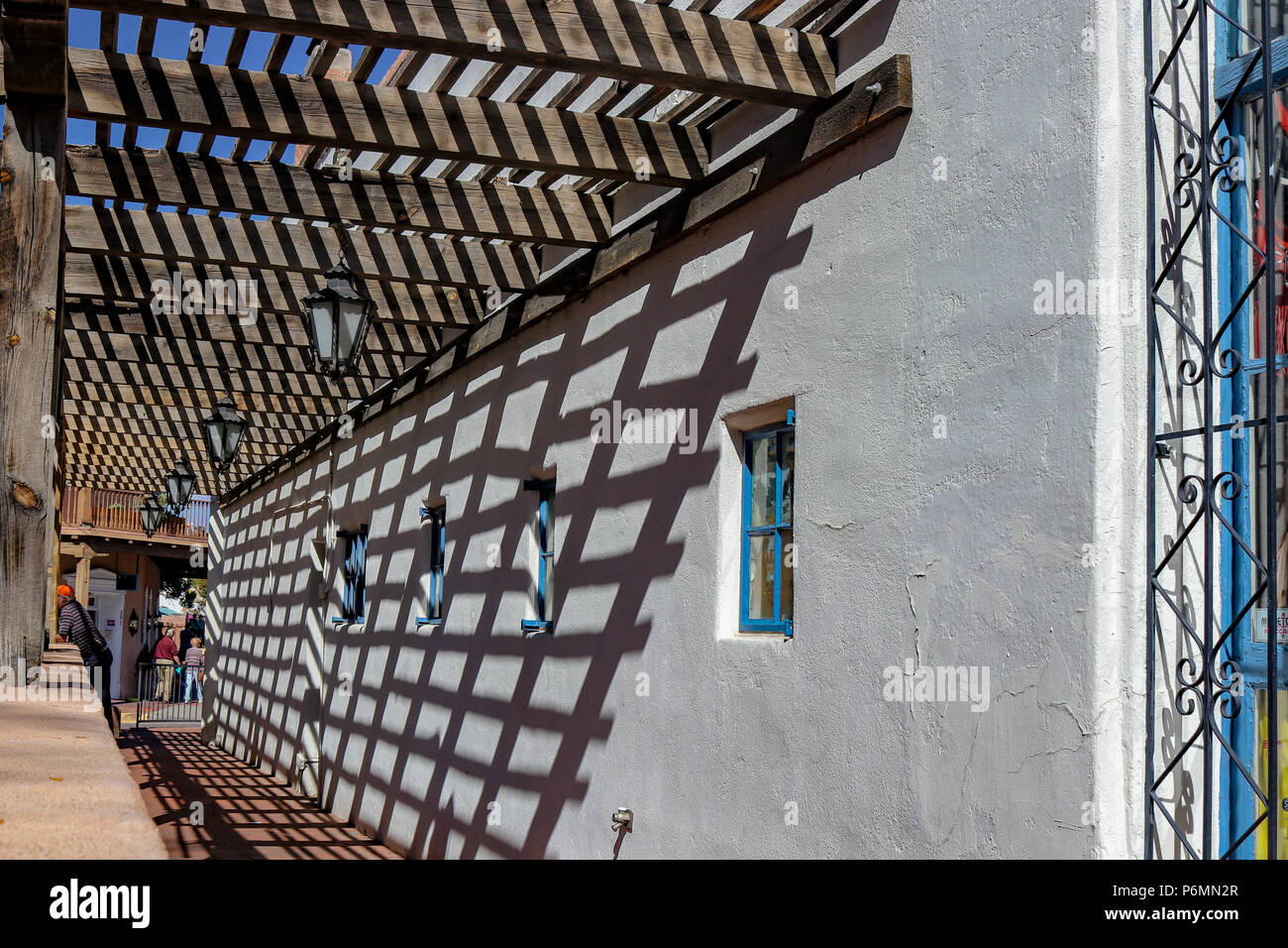 Schatten und Bürgersteigen. Das hölzerne Gitter wirft einen schönen Schatten gegen den Adobe Wand entlang einem Bürgersteig in der Altstadt von Albuquerque, New Mexico Stockfoto