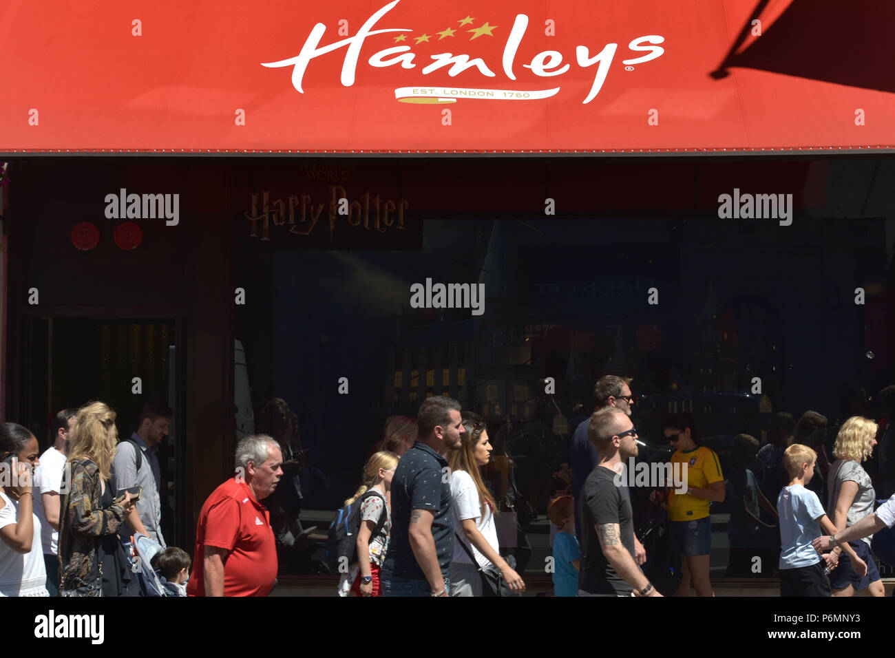 Kunden, Touristen und Mitarbeiter im Büro vorbei das Flaggschiff Hamleys Toy Store in der Regent Street in Central London im Sommer Sonnenschein. Stockfoto