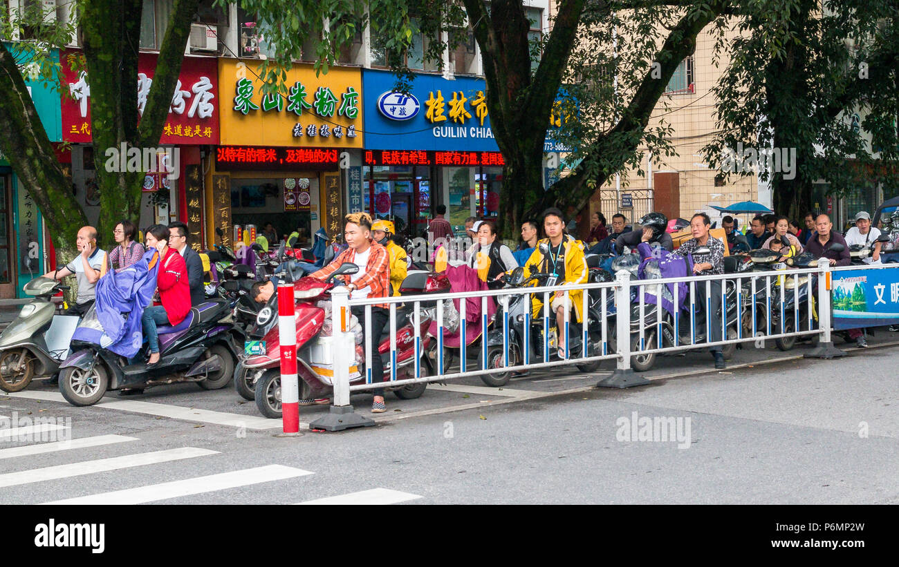 Szene asiatischen Straße mit Motorräder und Mopeds an der Haltestelle in der Nähe von Zebrastreifen in der Stadt Guilin in China Stockfoto