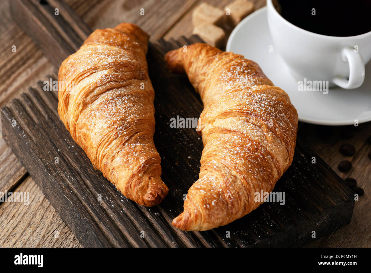 Croissants und Kaffee auf rustikalen Holztisch. Detailansicht. Kaffeepause mit Kaffee, Frühstück Konzept Stockfoto